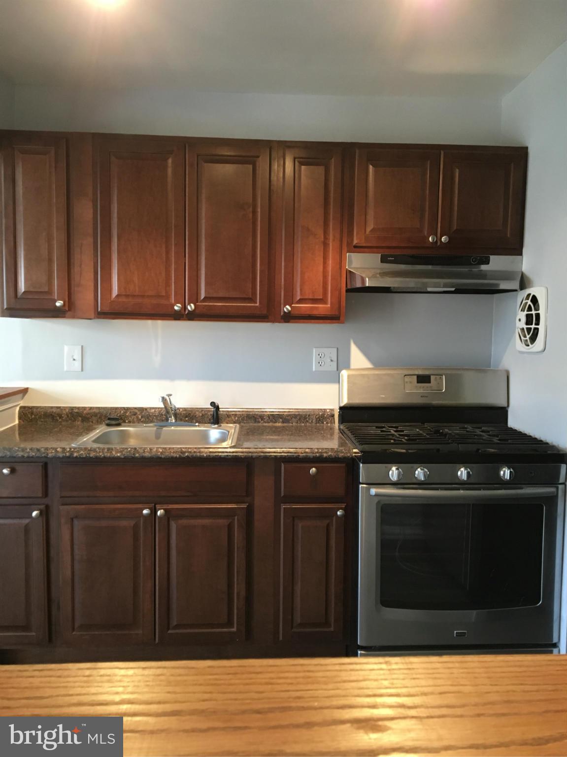 3803 St Barnabas Road, Unit T Suitland, MD 20746 - Photo 3 of 13 a kitchen with wooden cabinets and a stove top oven