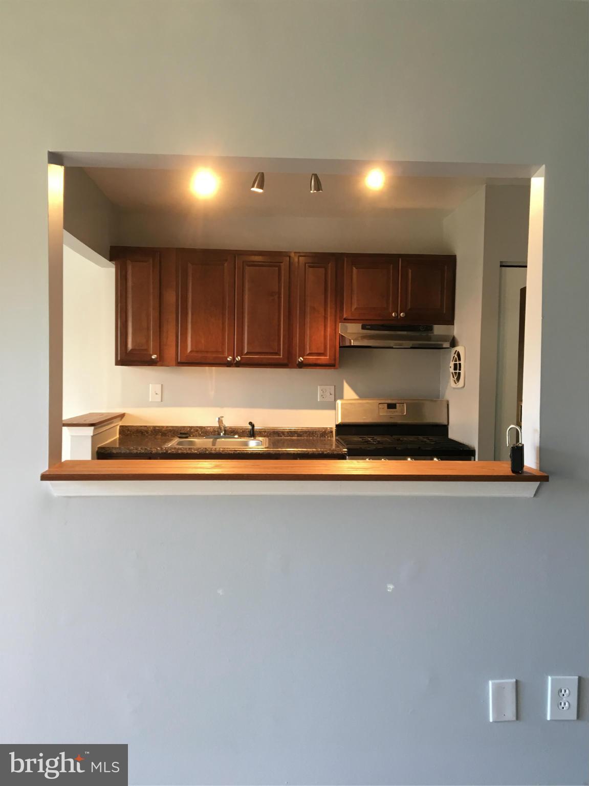 3803 St Barnabas Road, Unit T Suitland, MD 20746 - Photo 5 of 13 a large kitchen with stainless steel appliances a large counter top a stove and a refrigerator with wooden floor