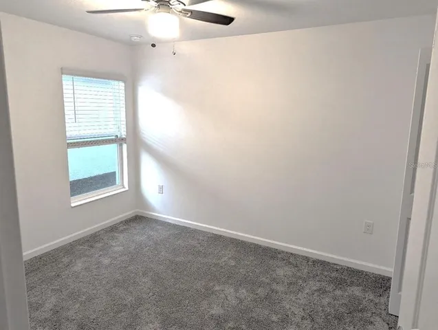 an empty room with windows and fan