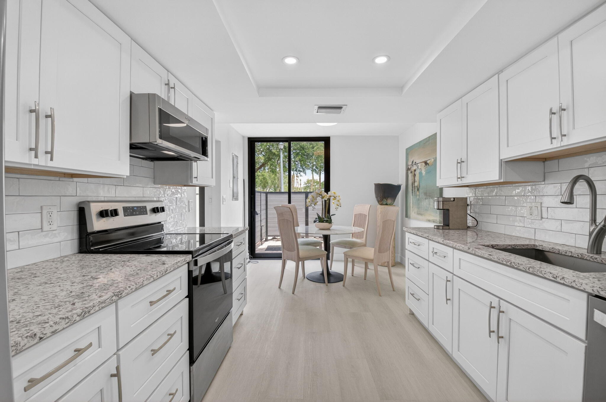 3708 Bridgewood Drive Boca Raton, FL 33434 - Photo 4 of 37 a kitchen with stainless steel appliances granite countertop a stove a sink dishwasher a refrigerator white cabinets and wooden floor next to a window