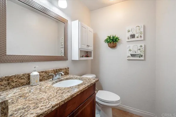 a bathroom with a granite countertop sink a toilet and a mirror