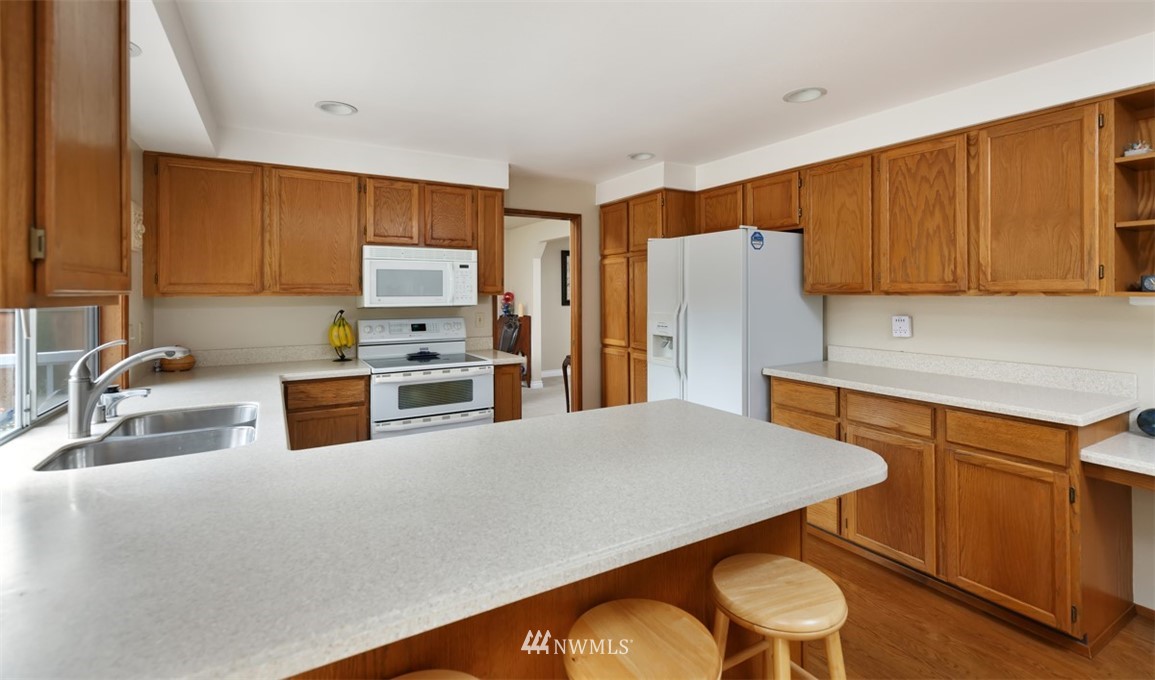 15720 Southeast 184th Street Renton, WA 98058 - Photo 18 of 30 a kitchen with stainless steel appliances wooden cabinets a stove a sink and a refrigerator