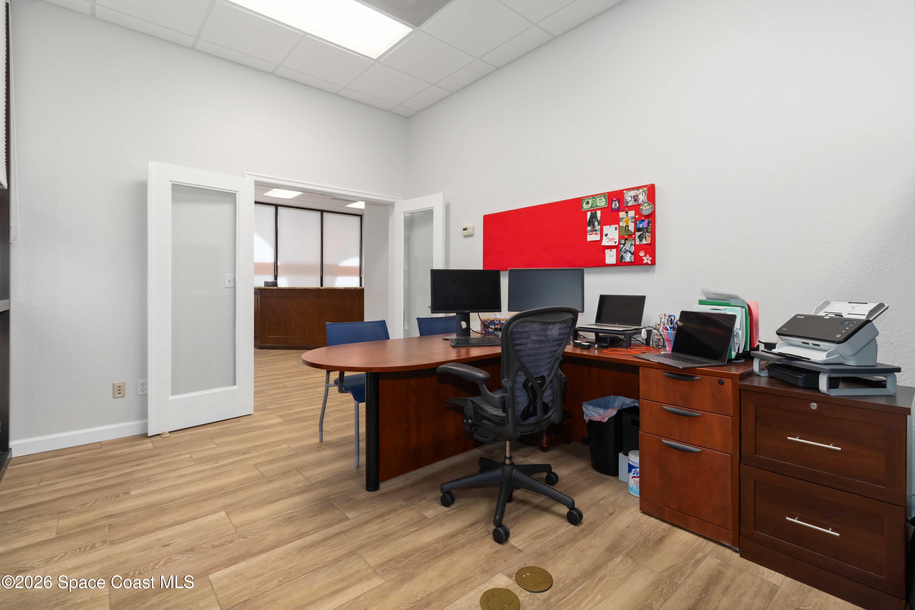 7730 North Wickham Road, Unit 101 Melbourne, FL 32940 - Photo 16 of 48 a view of a workspace with furniture and wooden floor