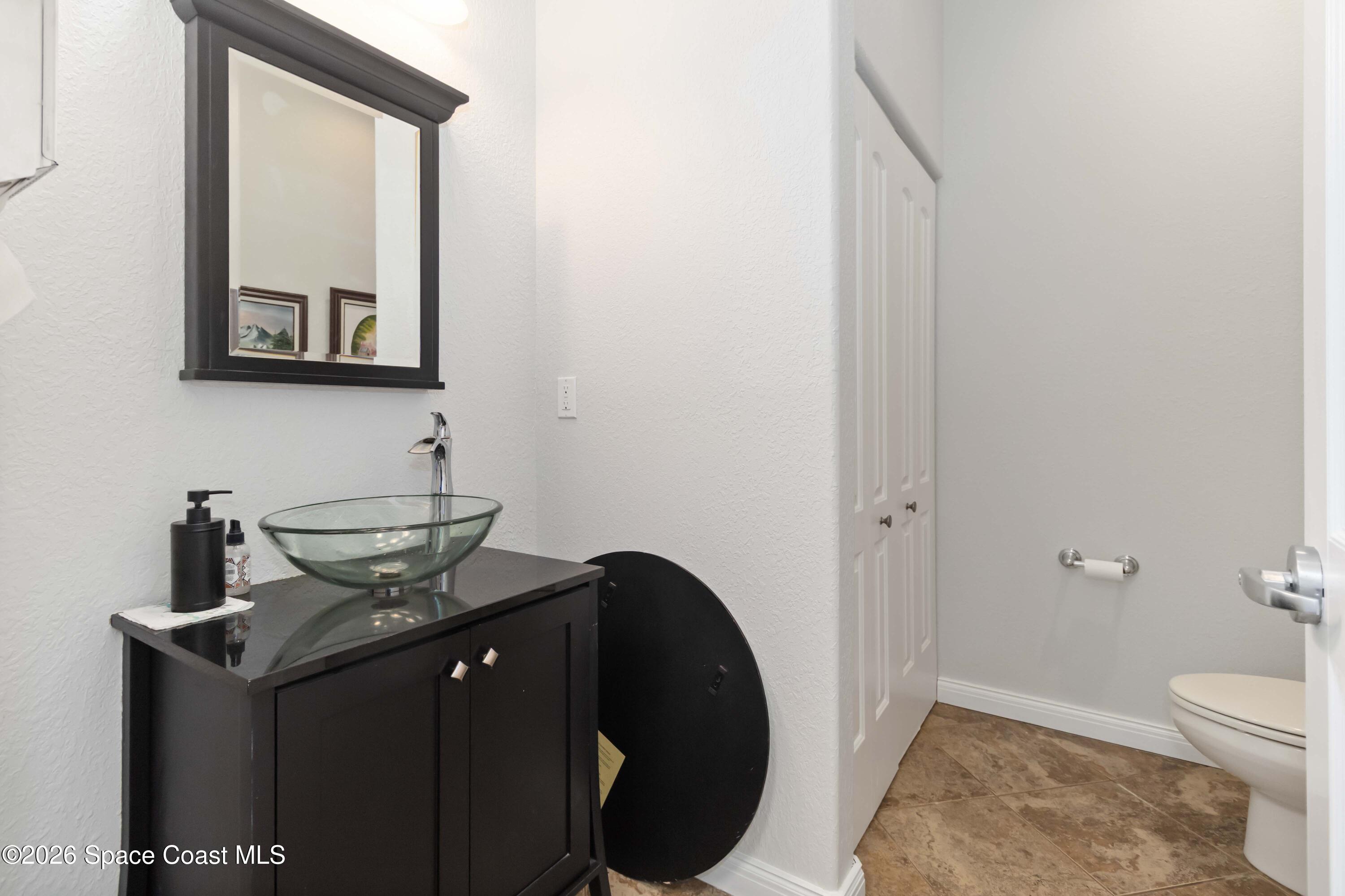 7730 North Wickham Road, Unit 101 Melbourne, FL 32940 - Photo 38 of 48 a bathroom with a granite countertop sink a toilet and mirror