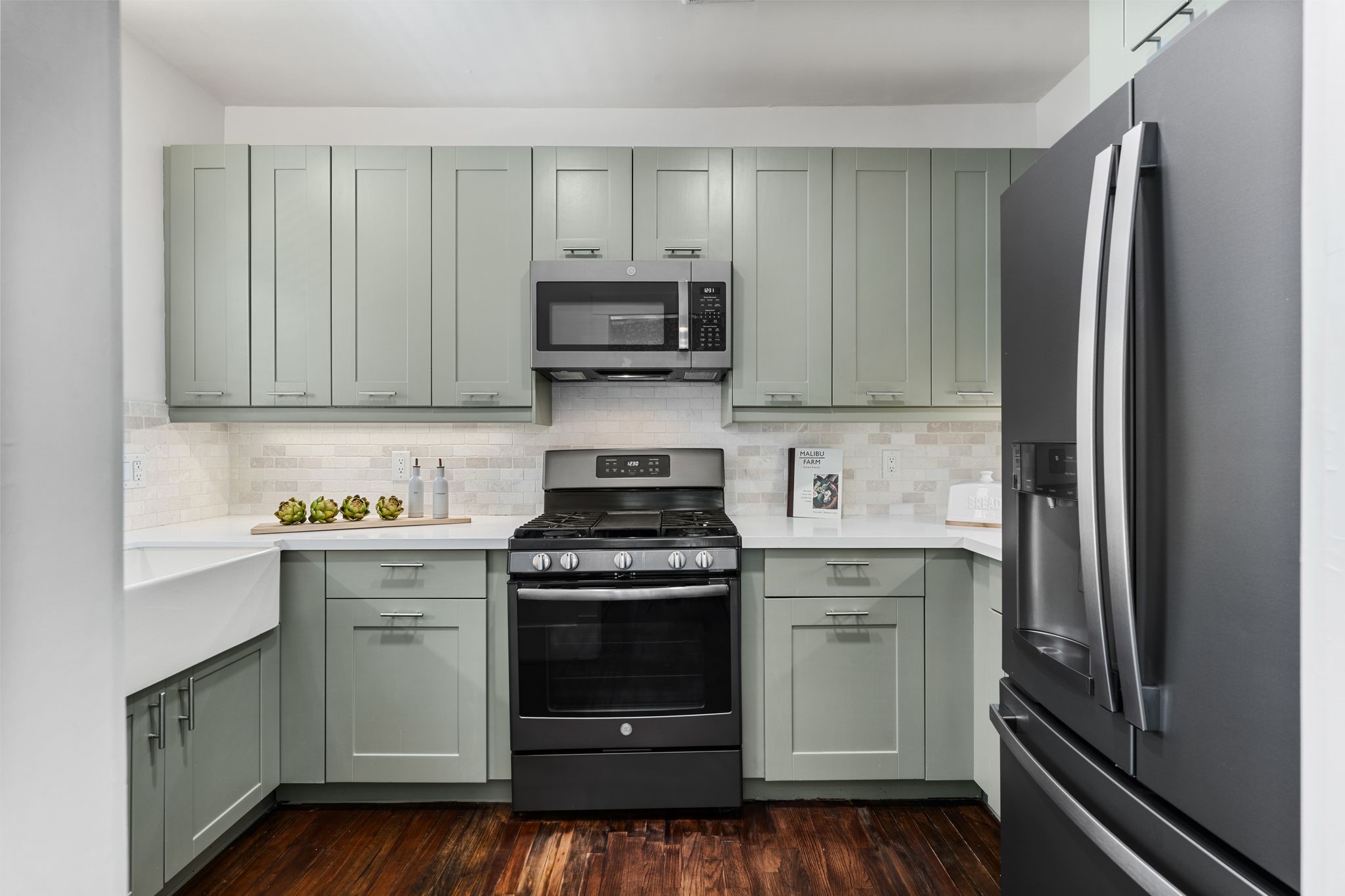 714 Ridge Street Houston, TX 77009 - Photo 10 of 36 The pristine kitchen impresses with sage green custom cabinetry, crisp white quartz countertops and tile backsplashes. Under-cabinet lighting and plenty of counter-level outlets add convenience to the charming kitchen.