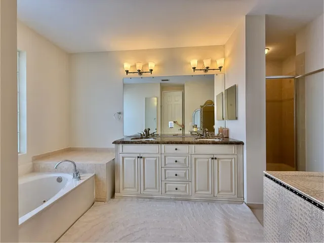 a bathroom with a granite countertop bathtub a sink and a mirror