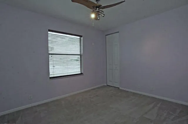 an empty room with a ceiling fan and window