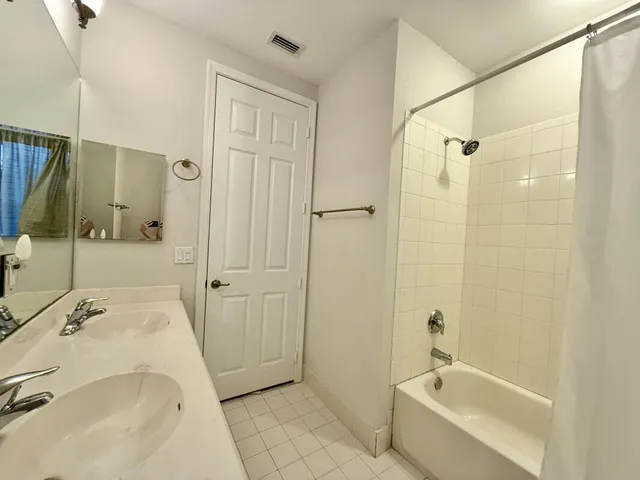 a bathroom with a tub sink vanity and a shower