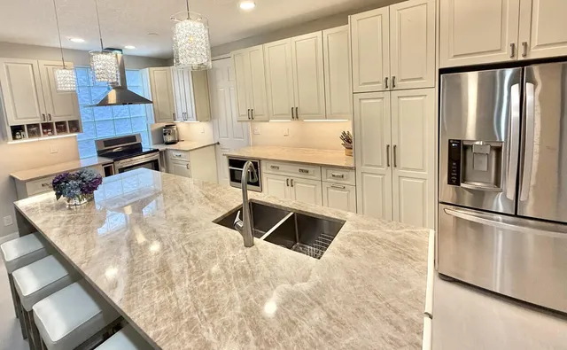 a kitchen with stainless steel appliances granite countertop a refrigerator a oven a sink and white cabinets