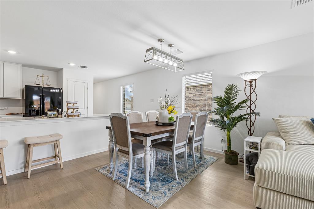 14163 Kempt Drive Pilot Point, TX 76258 - Photo 9 of 29 The dining area showcases an upgraded modern light fixture and open-concept design, creating a warm and welcoming space for everyday dining and entertaining.