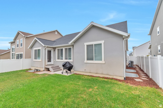 13038 Tower Ridge Drive Riverton, UT 84096 - Photo 30 of 30 Expansive backyard featuring a lush lawn, white privacy fencing, and a concrete patio with steps leading to an entryway