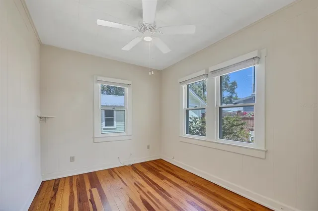 a view of an empty room with a window and wooden floor