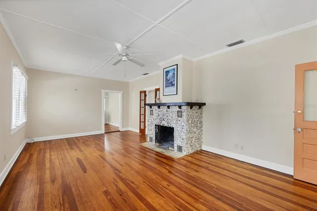 an empty room with wooden floor fireplace and windows