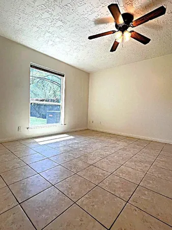 a view of an empty room and window & a ceiling fan