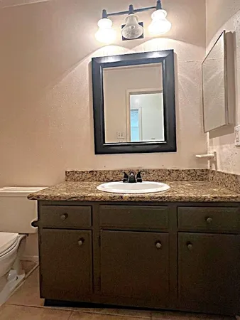 a bathroom with a granite countertop sink a large mirror and a toilet