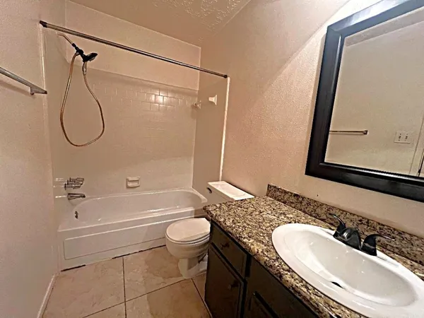 a bathroom with a granite countertop sink toilet a mirror a vanity and bathtub