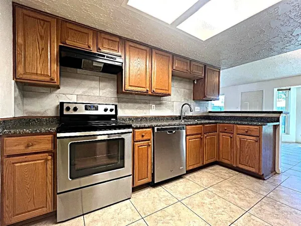 a kitchen with granite countertop a stove top oven microwave and cabinets