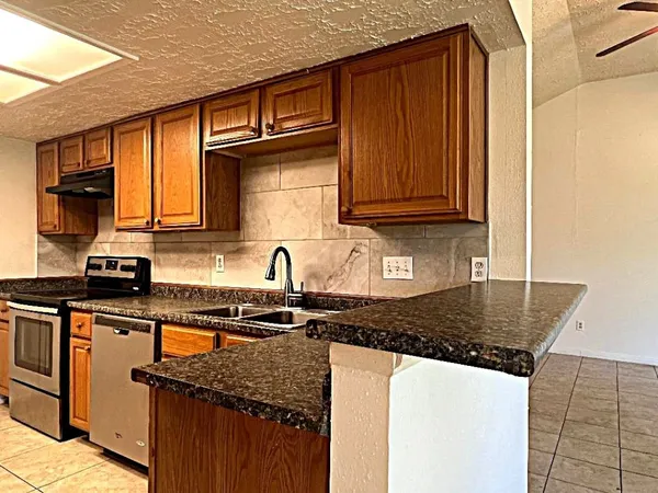 a kitchen with granite countertop a sink a stove and cabinets