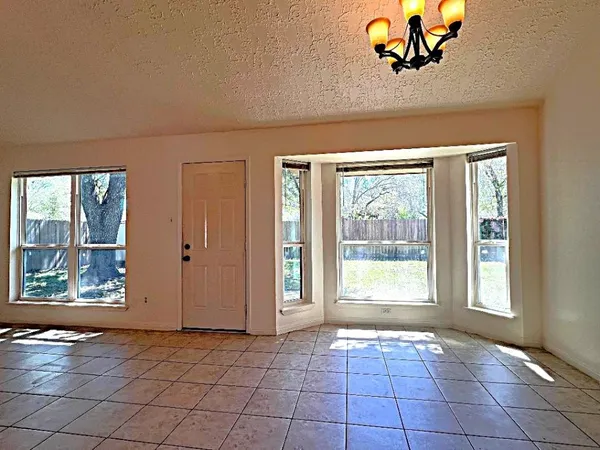 an empty room with windows and chandelier fan