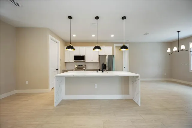 a view of a kitchen with kitchen island a sink stainless steel appliances and a counter top space