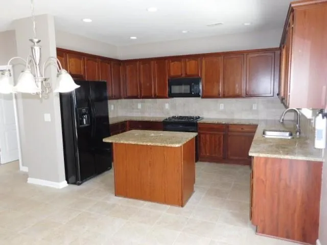 a kitchen with stainless steel appliances granite countertop wooden cabinets a refrigerator and a sink