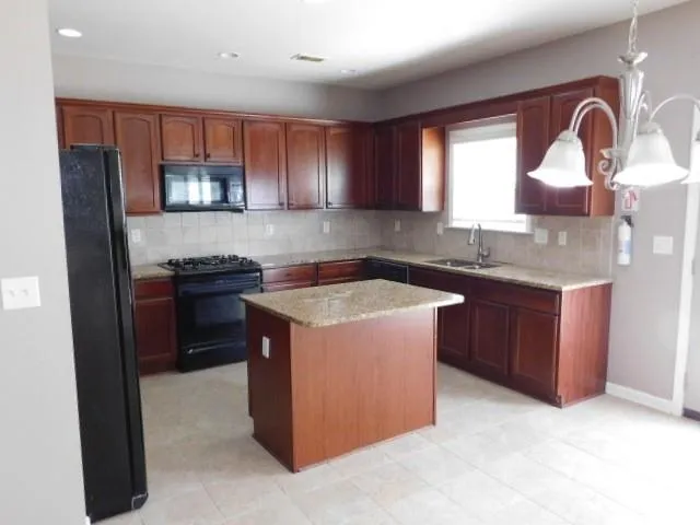 a kitchen with stainless steel appliances granite countertop a stove a sink a refrigerator and a microwave