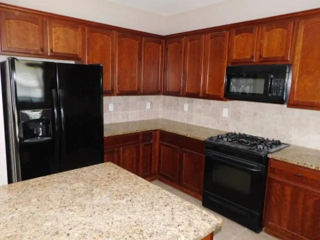 a kitchen with granite countertop wooden cabinets and stainless steel appliances