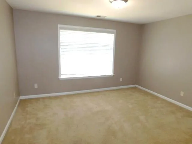 a view of an empty room with wooden floor and a bathroom