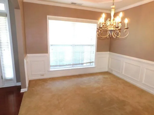 a view of empty room with window and chandelier