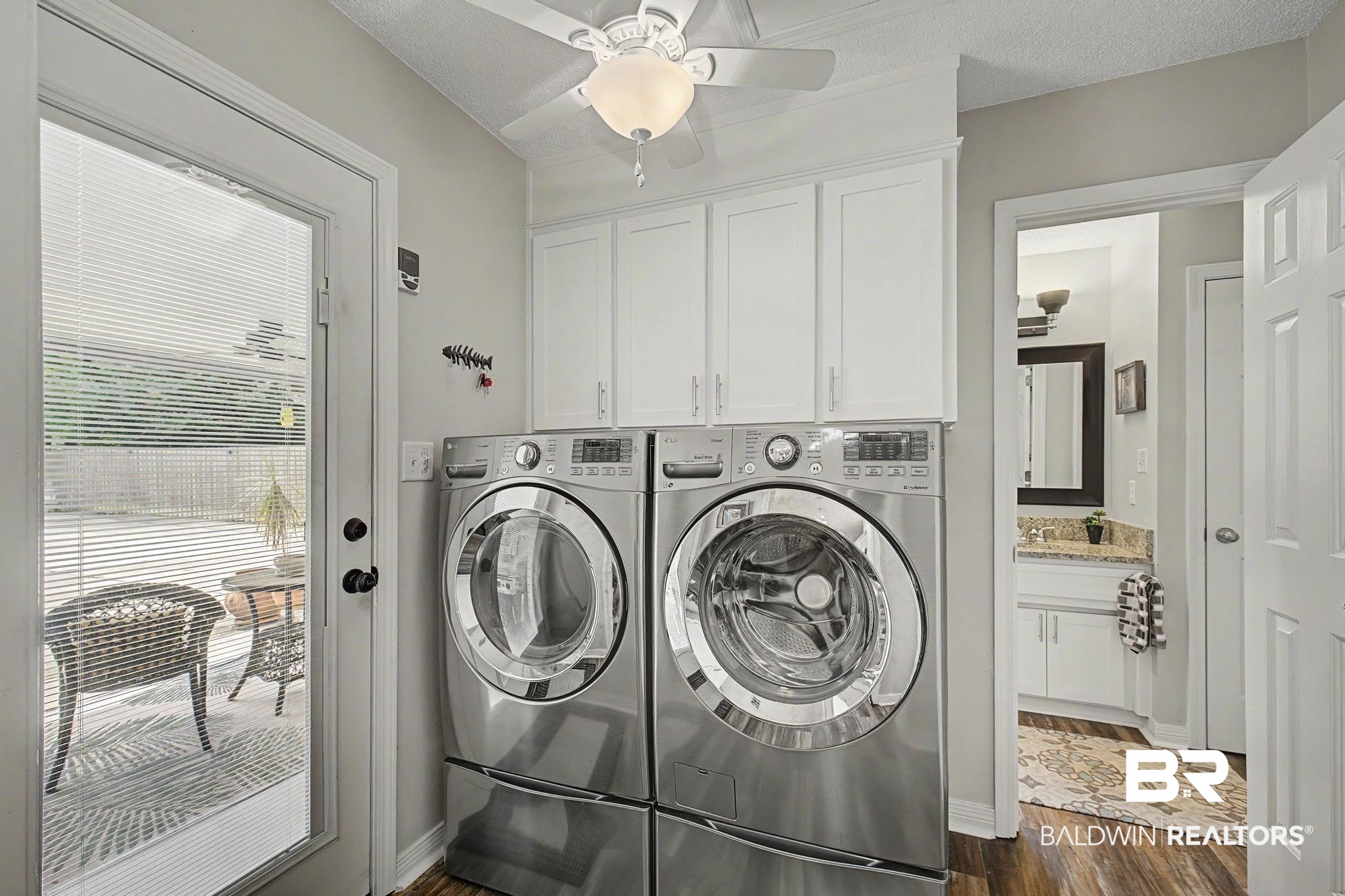 2808 Pine Ridge Drive Lillian, AL 36549 - Photo 24 of 47 Laundry area featuring stacked front-load machines, white cabinetry, wood-finish flooring, and a ceiling fan