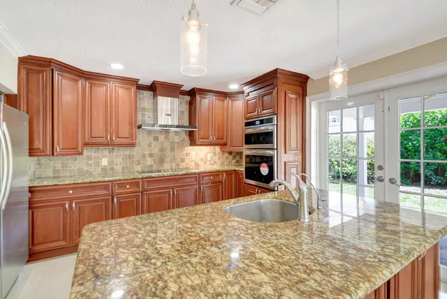 a kitchen with kitchen island granite countertop a sink stove and cabinets