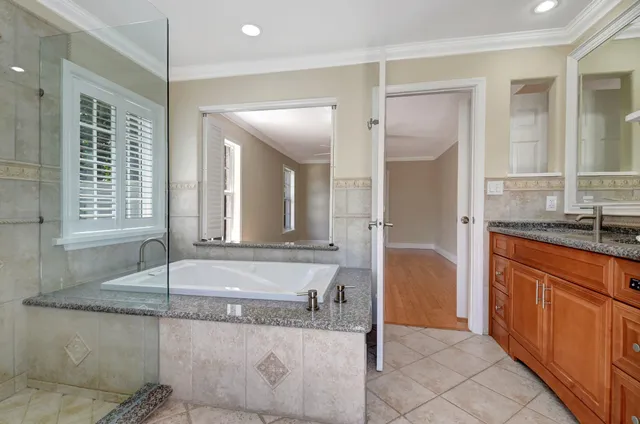 a bathroom with a granite countertop tub sink and mirror
