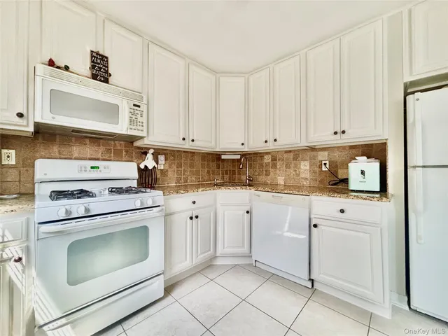 a kitchen with granite countertop white cabinets and white appliances
