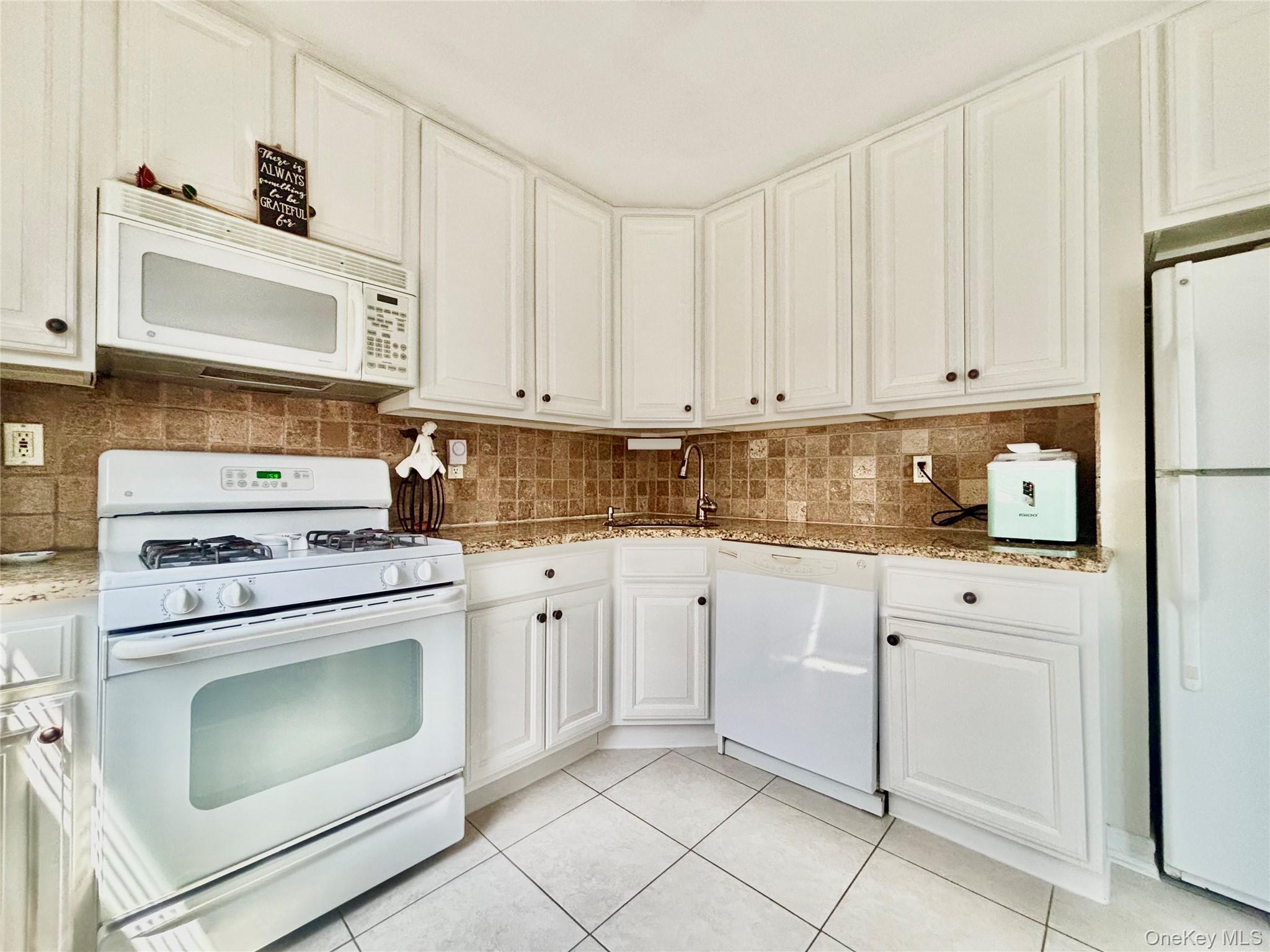 72-29 Little Neck Parkway, Unit 2 Queens, NY 11426 - Photo 5 of 24 a kitchen with granite countertop white cabinets and white appliances