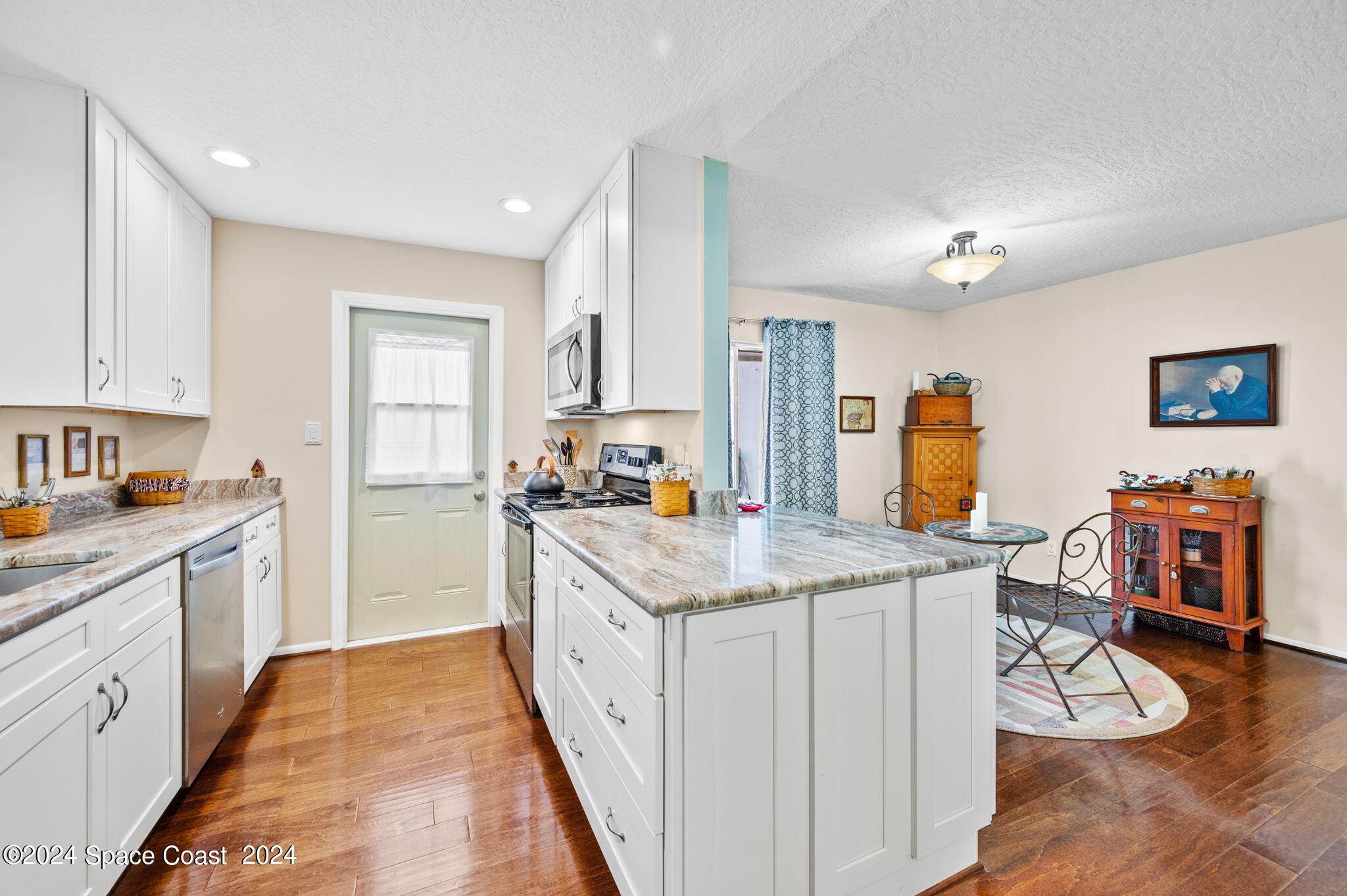 897 Brunswick Lane Rockledge, FL 32955 - Photo 9 of 41 a kitchen with a stove a refrigerator a sink dishwasher with a dining table and chairs with wooden floor