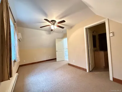 an empty room with chandelier fan and windows