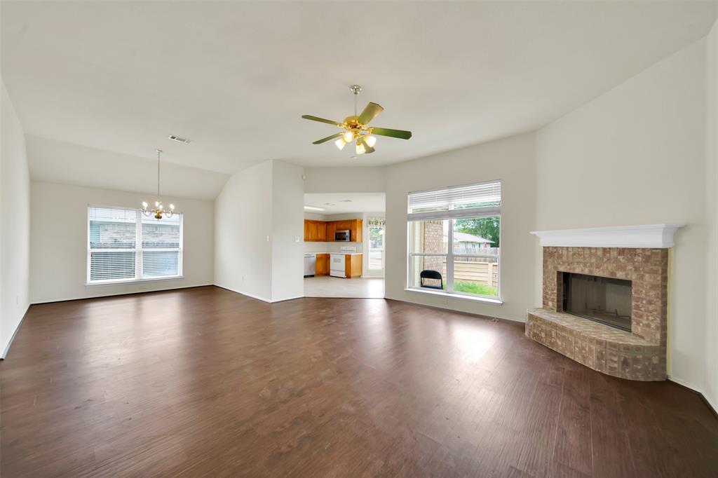 4221 Fiste Denton, TX 76207 - Photo 4 of 26 Unfurnished living room with ceiling fan with notable chandelier, dark hardwood / wood-style floors, vaulted ceiling, and a brick fireplace