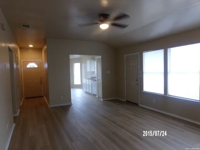 an empty room with wooden floor and windows