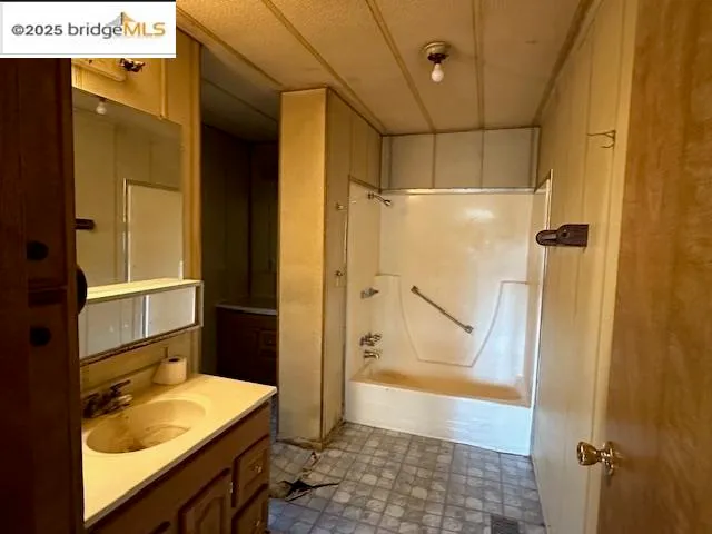 a bathroom with a tub sink vanity granite and shower