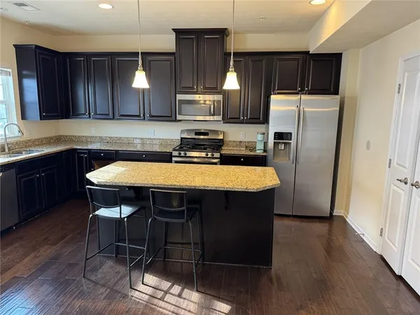 a kitchen with stainless steel appliances a dining table chairs refrigerator and microwave