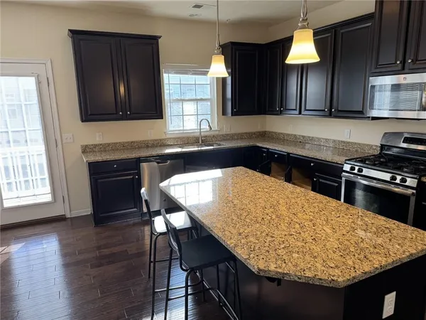 a kitchen with granite countertop wooden cabinets a stove a sink and a microwave