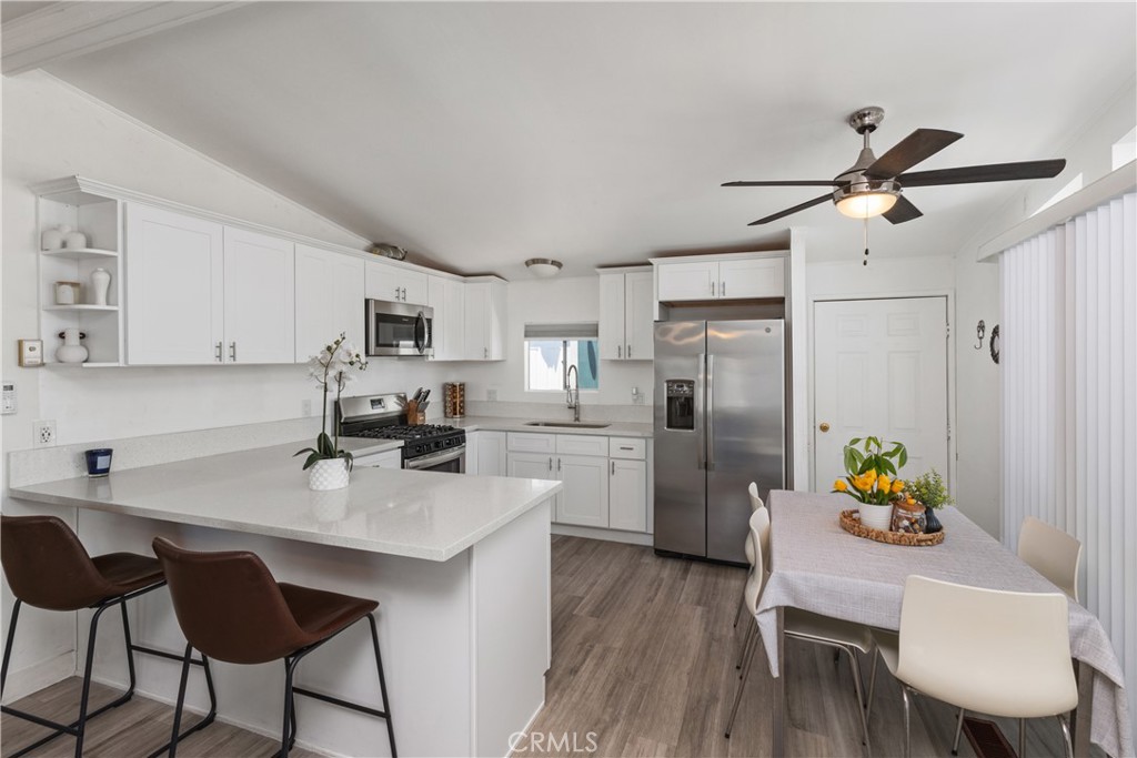 a kitchen with a dining table chairs refrigerator and microwave
