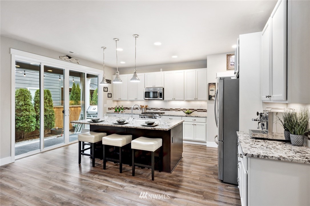 3615 177th Street Southeast Bothell, WA 98012 - Photo 4 of 32 a kitchen with stainless steel appliances granite countertop a table chairs refrigerator and microwave