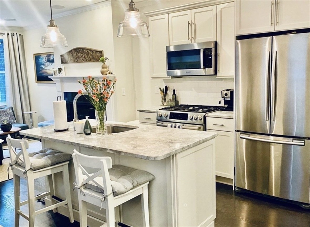 a kitchen with stainless steel appliances granite countertop a sink stove refrigerator and microwave
