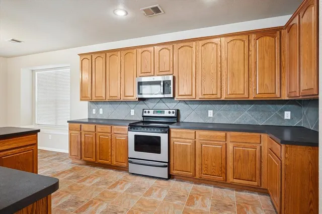 a kitchen with stainless steel appliances granite countertop a stove a sink and a microwave