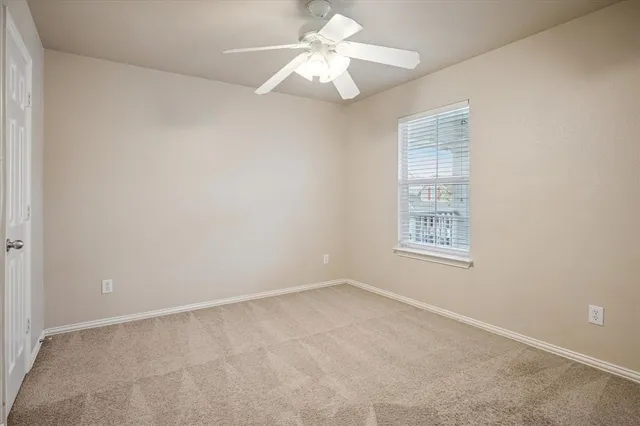 an empty room with a window and a fan