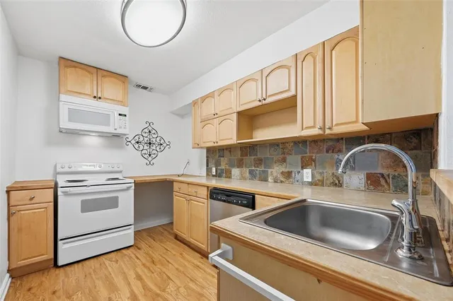 a kitchen with stainless steel appliances granite countertop a sink and cabinets with wooden floor