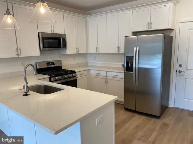 a kitchen with stainless steel appliances a refrigerator a sink a stove a microwave and wooden cabinets