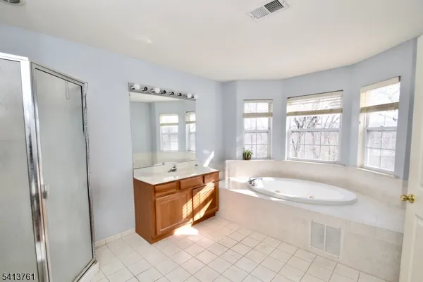 a spacious bathroom with a tub sink and mirror