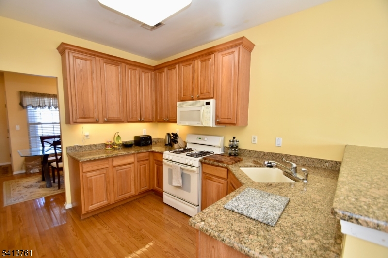263 Ridge Drive Pompton Lakes, NJ 07442 - Photo 7 of 20 a kitchen with stainless steel appliances granite countertop a stove top oven a sink dishwasher and cabinets with wooden floor